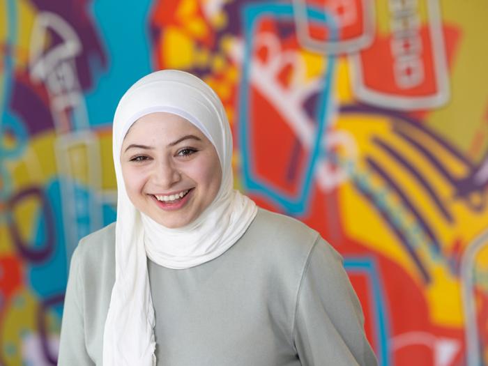 CU Denver student smiling for camera with colorful mural in background