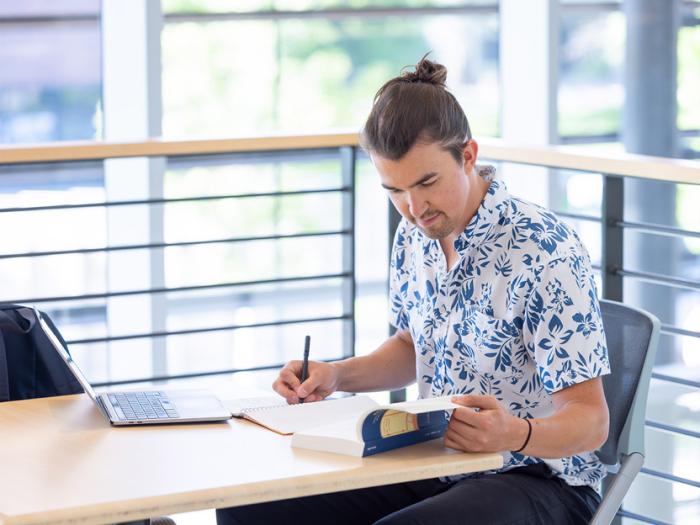 CU Denver student reading book while at sitting at a table