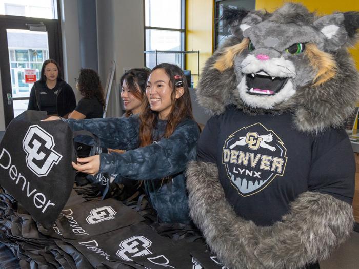 CU Denver students standing with Milo the Lynx handing out CU Denver bags