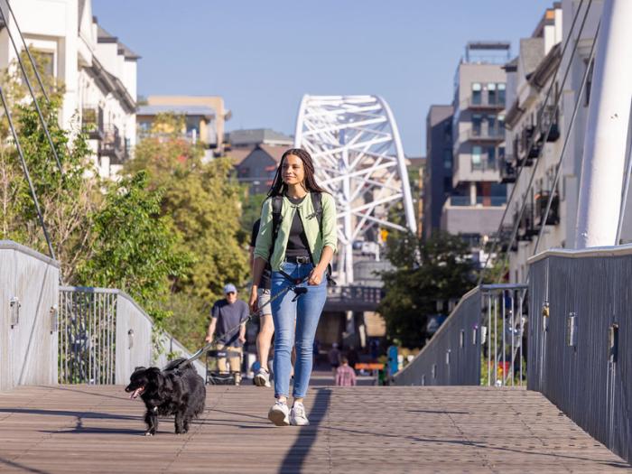 CU Denver student walking on bridge with their dog