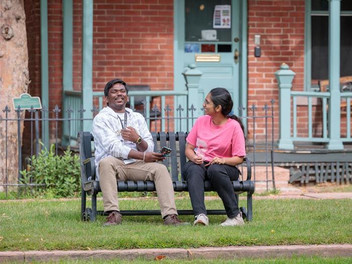 Two people sitting on bench in front of house on Historic 9th Street