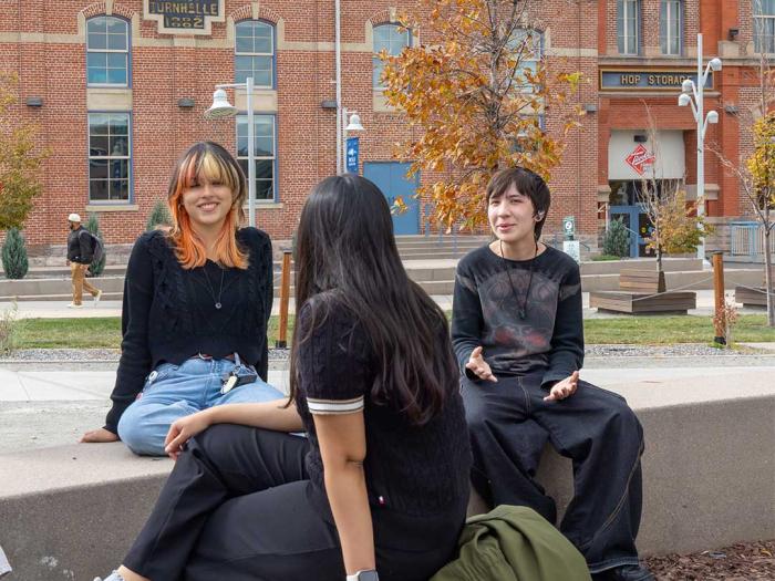 Three CU Denver students sitting outside of Tivoli building