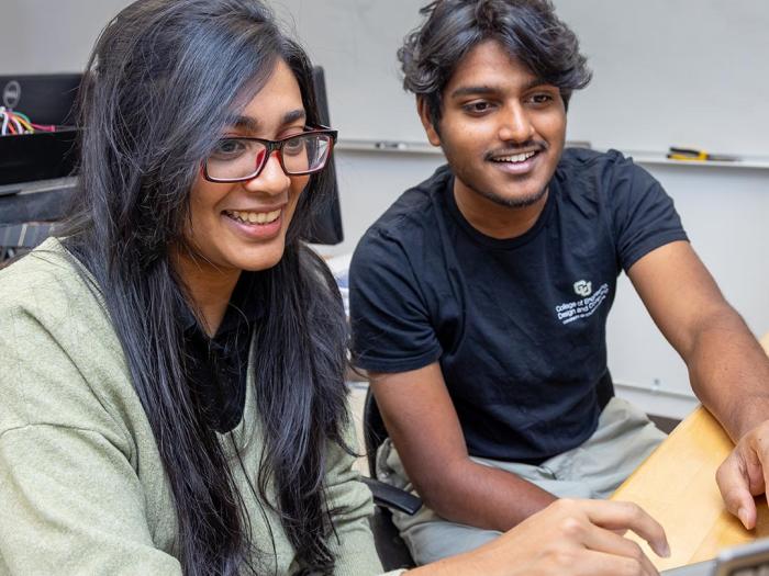 Two students working on laptop in class