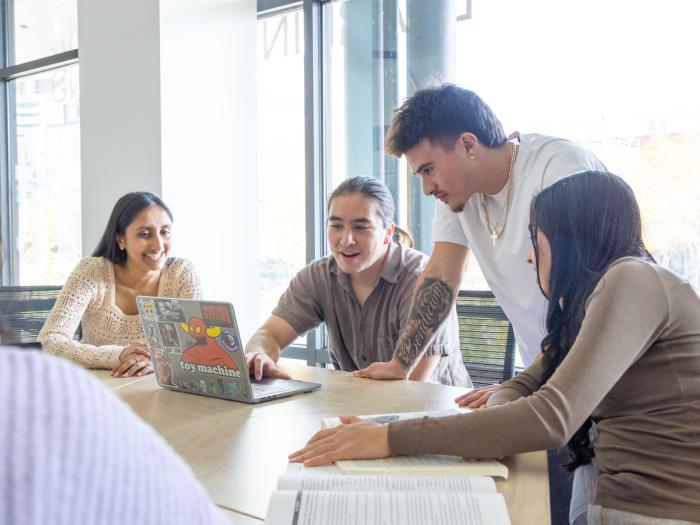 Students sitting at table around a laptop