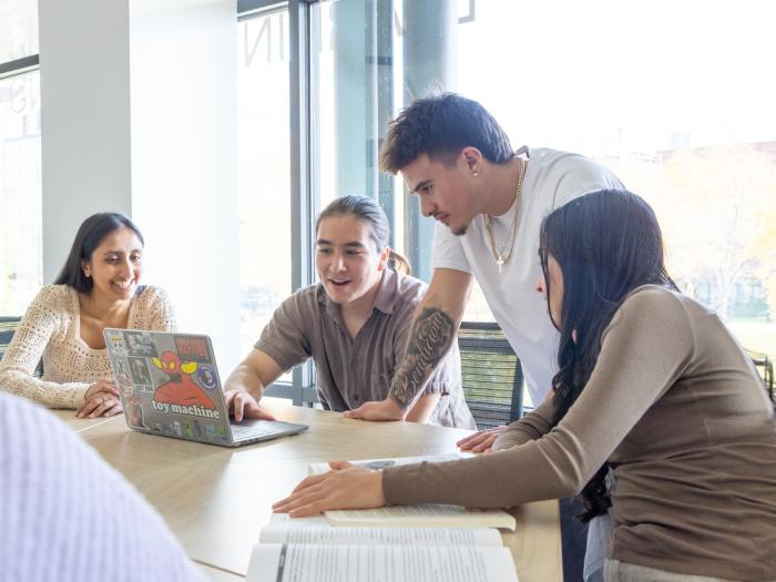 Students sitting at table around a laptop