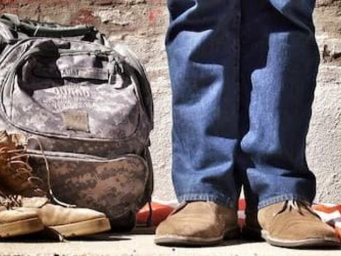 Person standing next to US flag and army boots