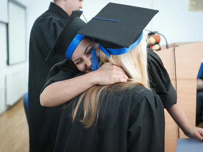 Two students embracing during a graduation ceremony