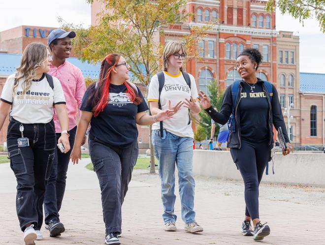 CU Denver students walking on sidewalk in front of Tivoli building talking amongst each other