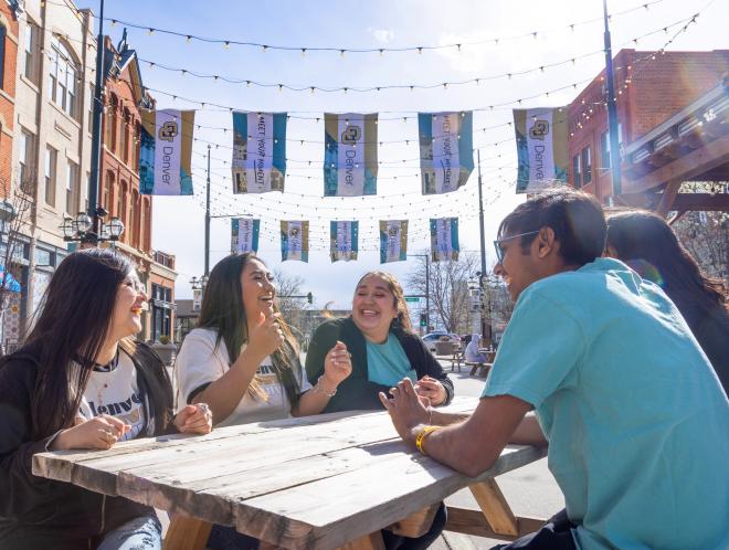 Students sitting at picnic table in Larimer Square