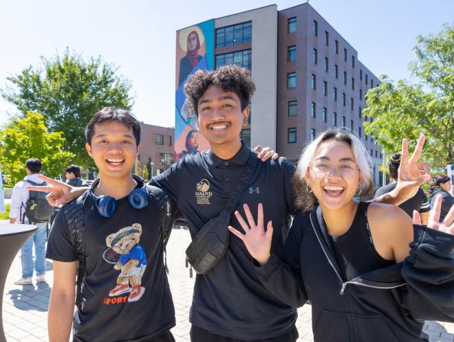 Three CU Denver students smiling and waving for camera