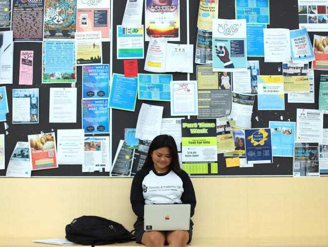 Student in front of wall of fliers