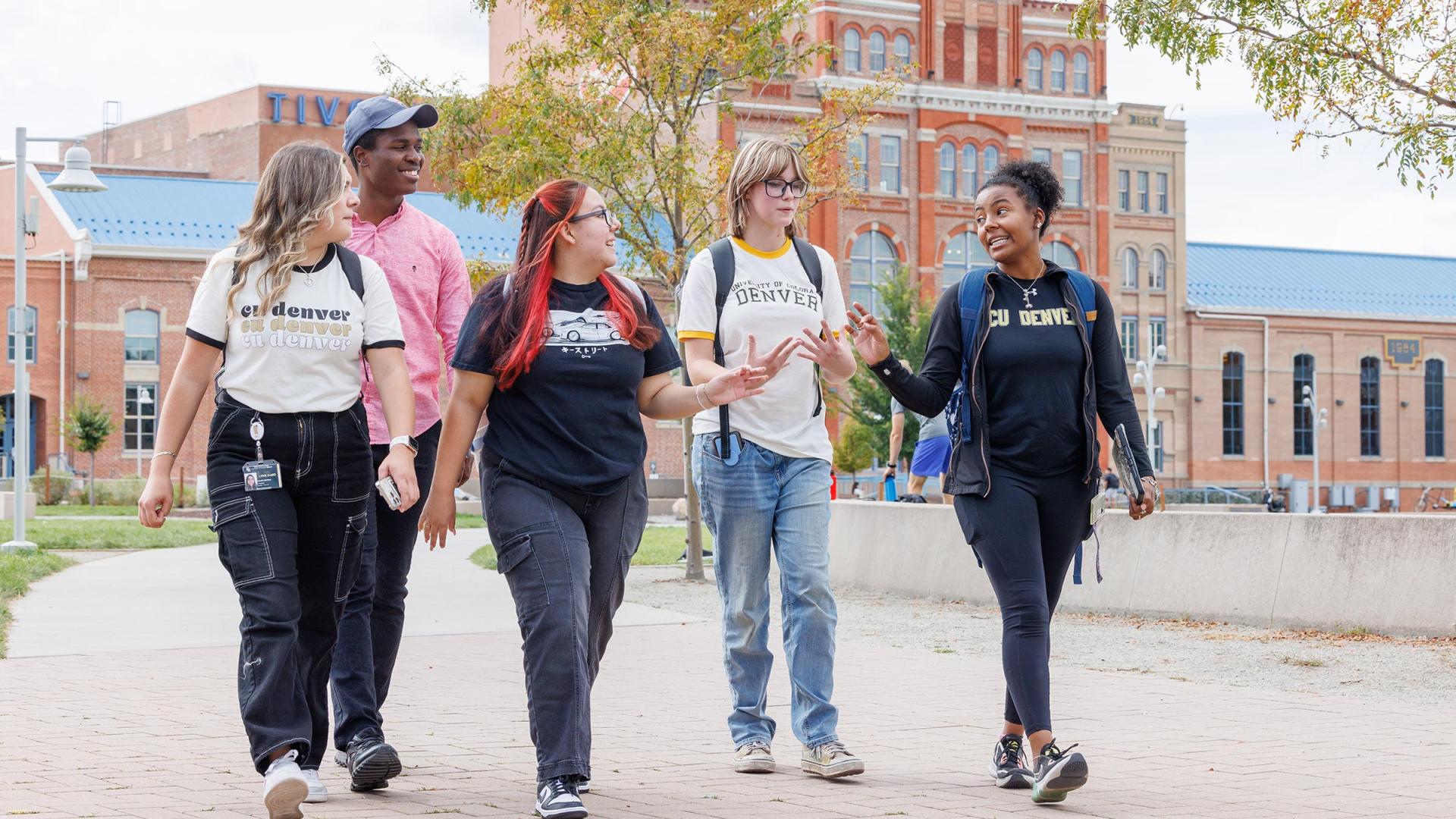 CU Denver students walking on sidewalk in front of Tivoli building talking amongst each other