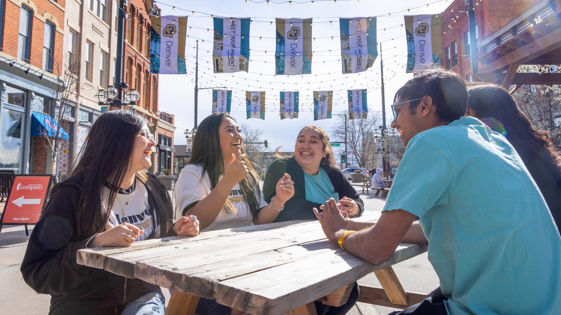 Students sitting at picnic table in Larimer Square