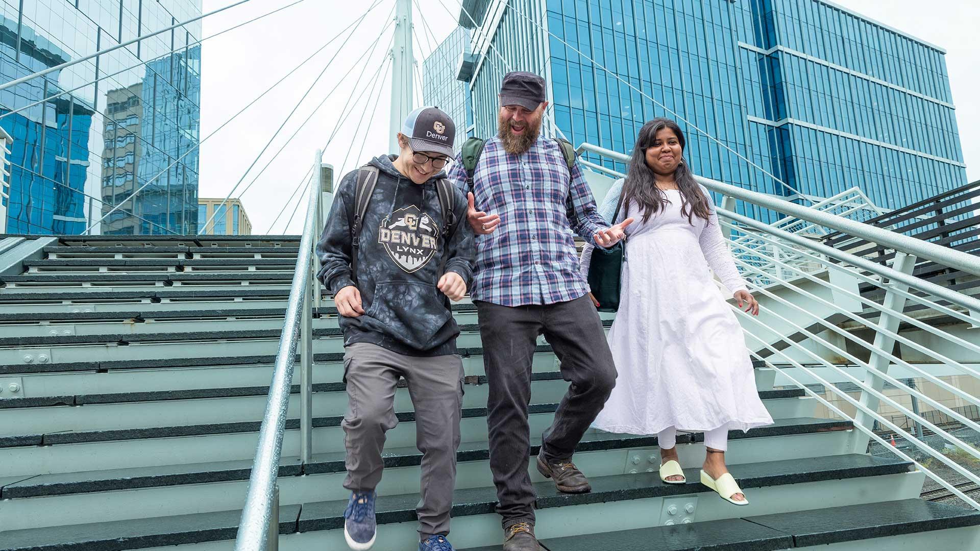 Three students walking down steps outside