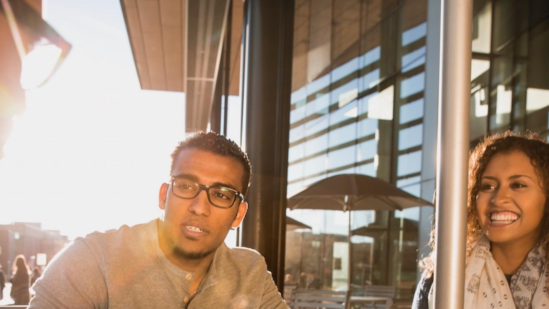 Three students sitting and talking outside of the Student Commons Building