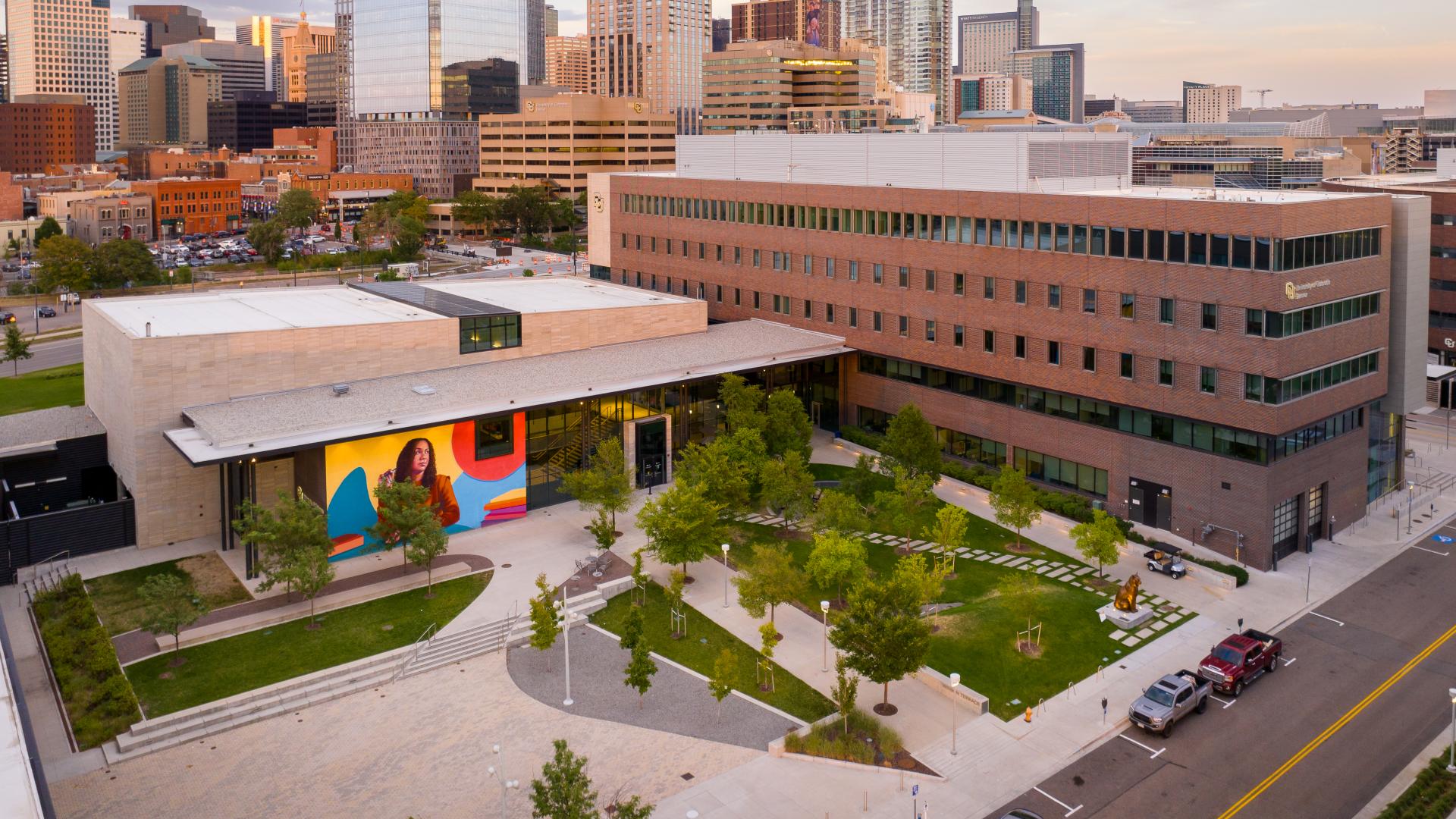 Drone shot of CU Denver Benson Terrace and Student Commons Building at sunset with the Denver skyline in the background.
