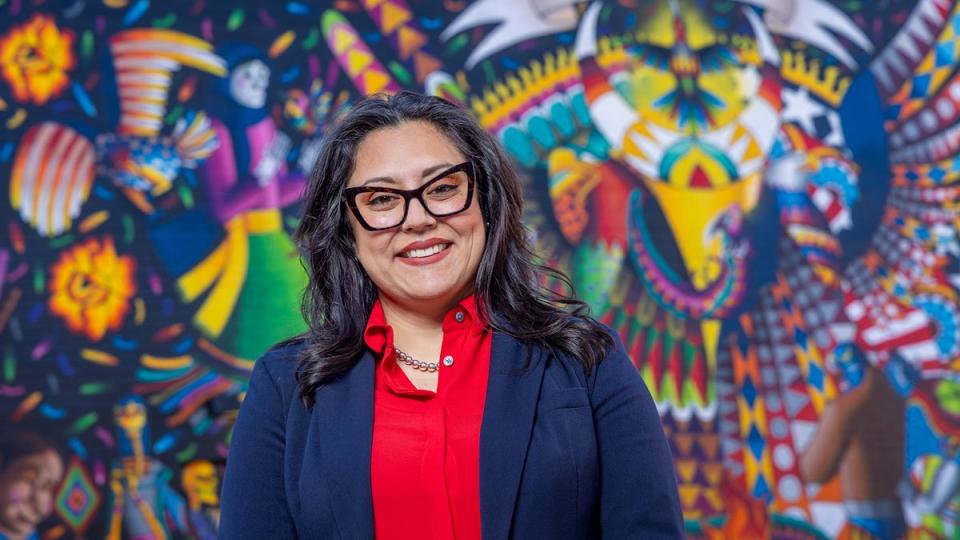 CU Denver alumn, Andrea Albo, standing in front of mural on campus