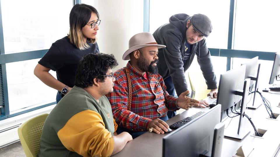Four CU Denver students working on project while sitting in computer lab