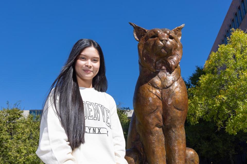 Student standing with Milo the Lynx statue