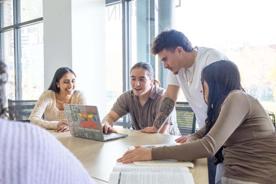 Students sitting at table around a laptop
