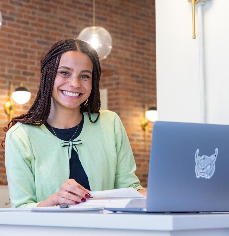 Student sitting in front of laptop smiling at camera