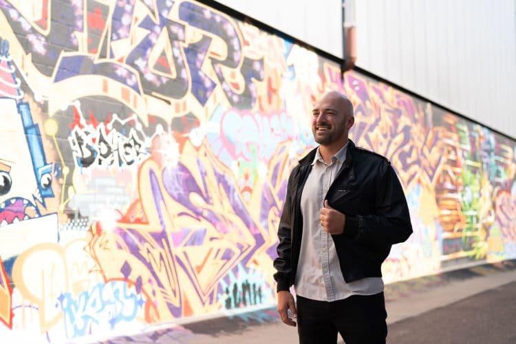 Man standing in front of wall with street art