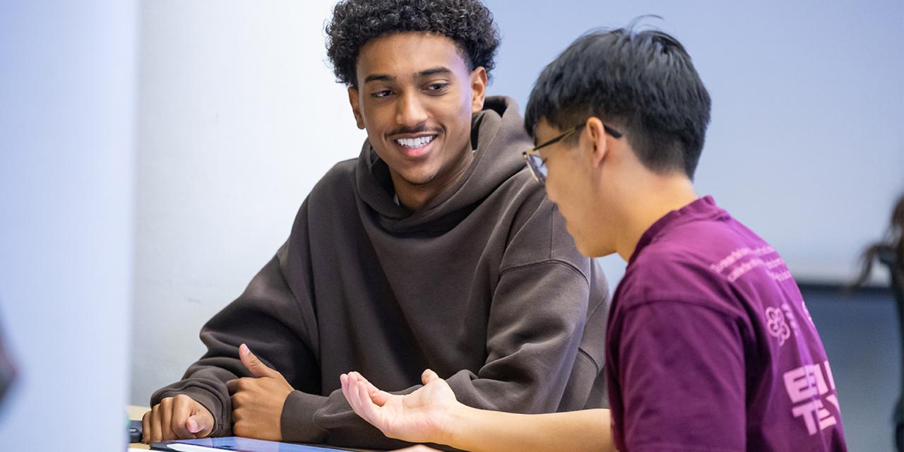 Two CU Denver students sitting down at table talking to one another