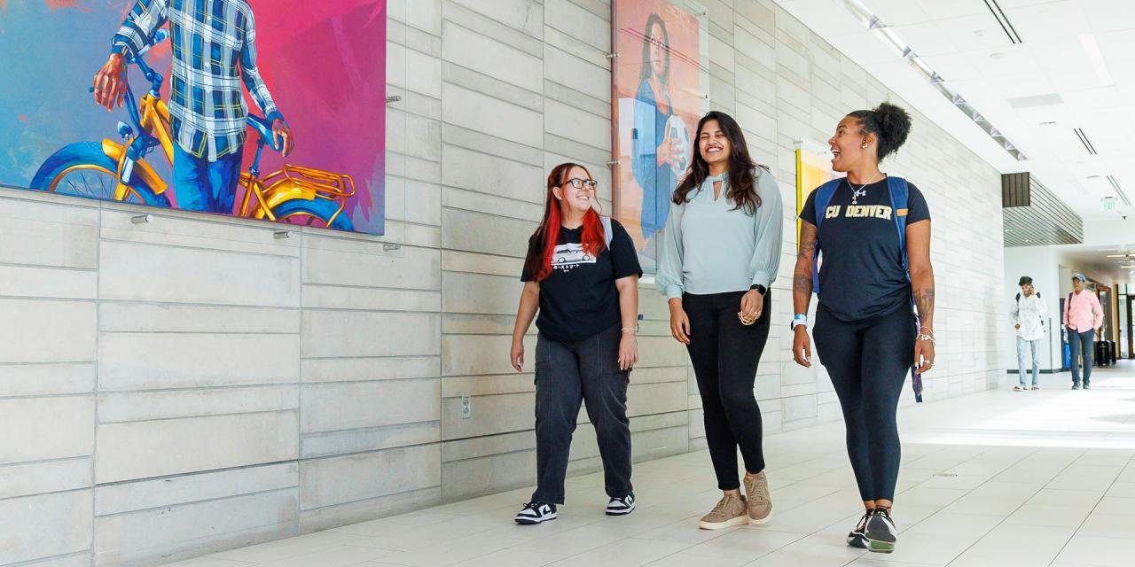 Students walking down hallway in student center with student art hanging on walls