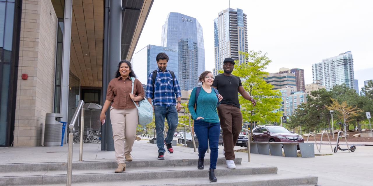 Four CU Denver students walking down stairs of Business school building