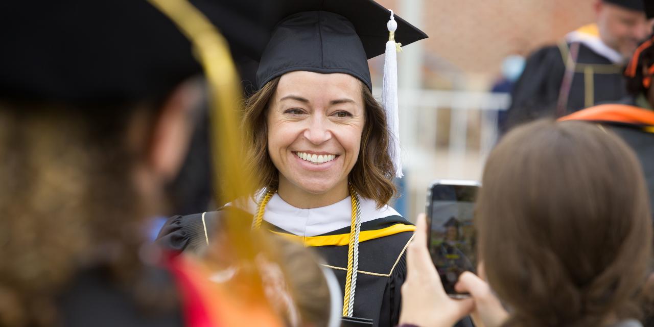 Graduate student smiling with cap and gown