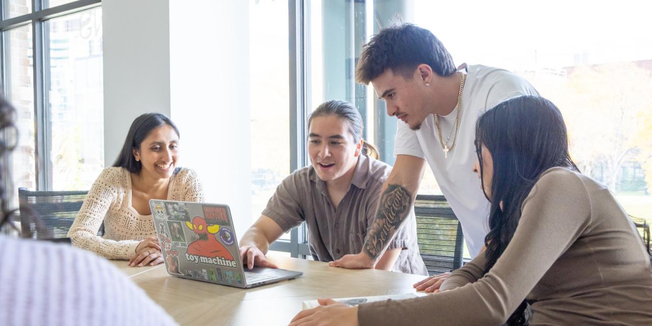 Students sitting at table around a laptop