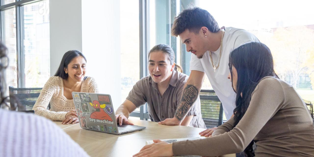 Students sitting at table around a laptop
