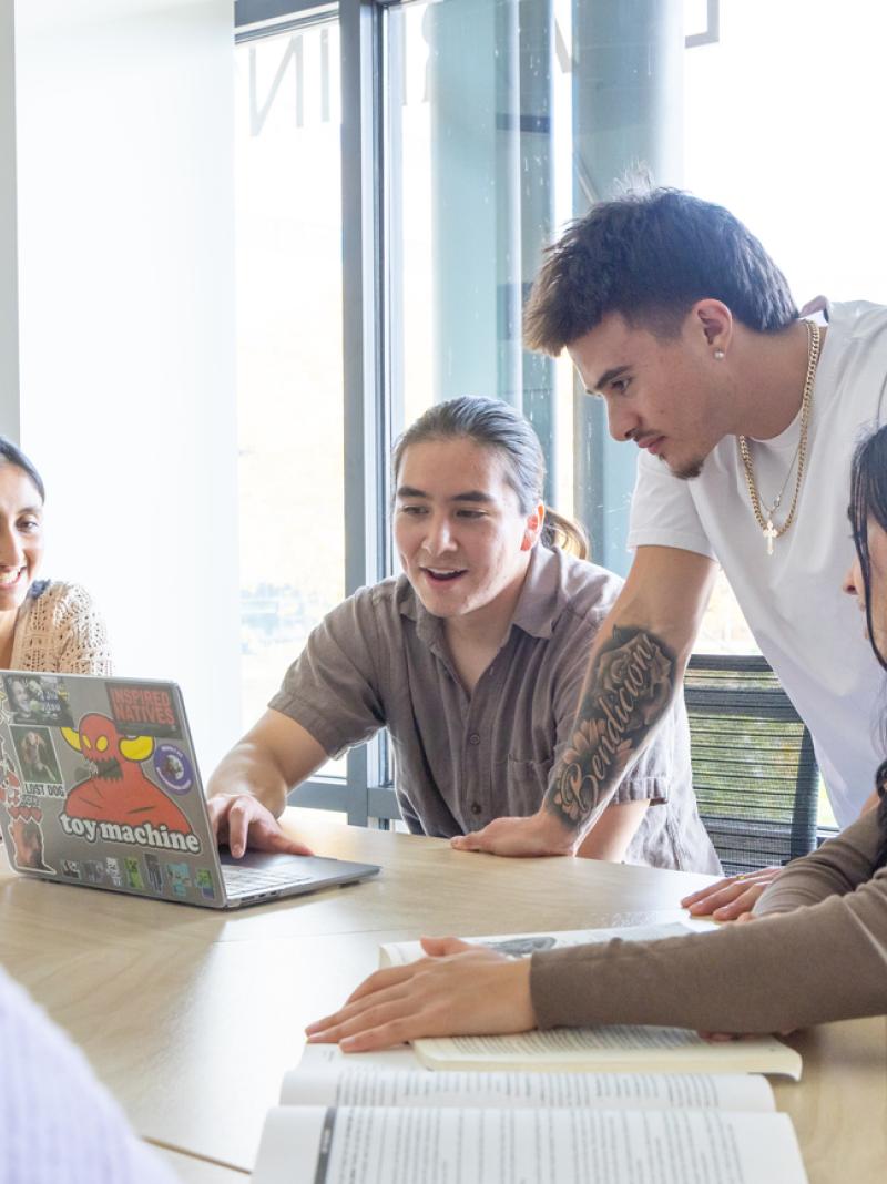 Students sitting at table around a laptop