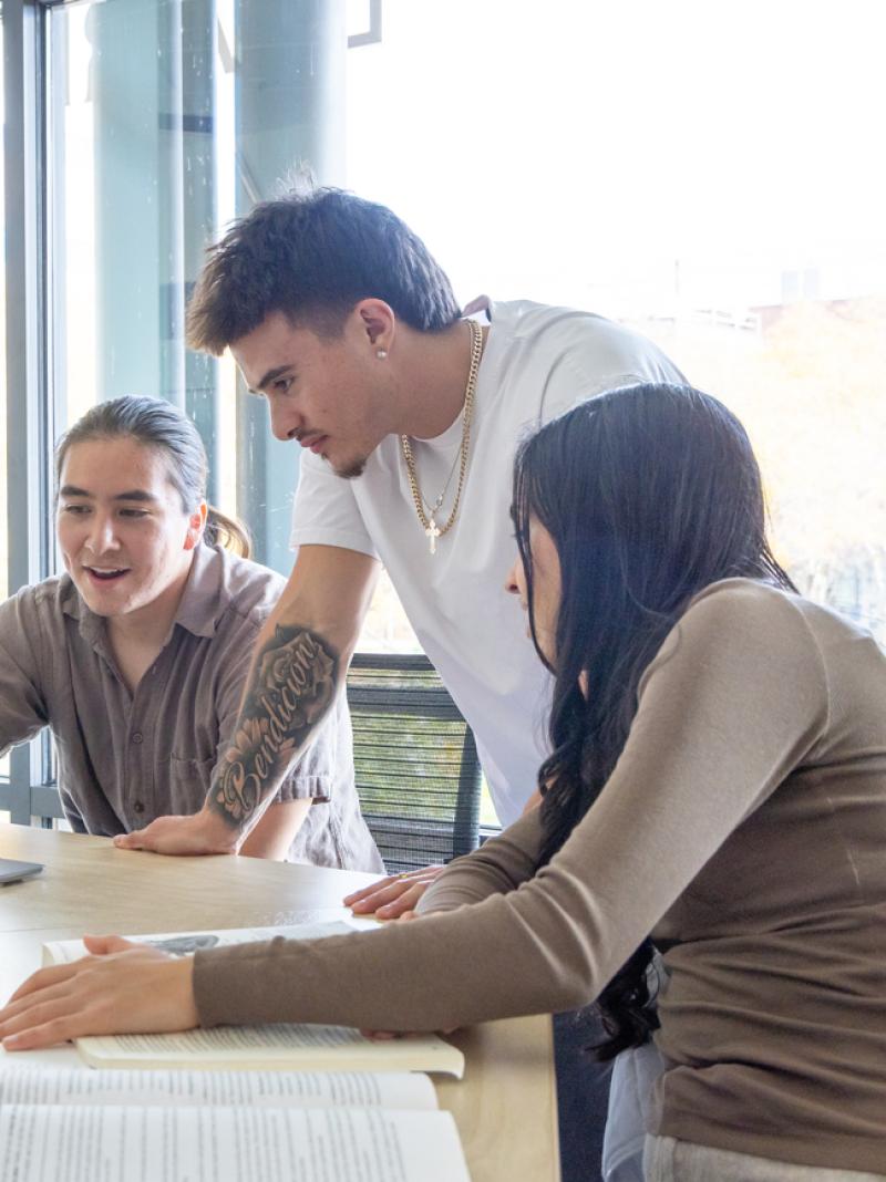 Students sitting at table around a laptop