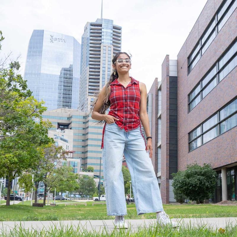CU Denver student wearing backpack posing on sidewalk with hand on hip