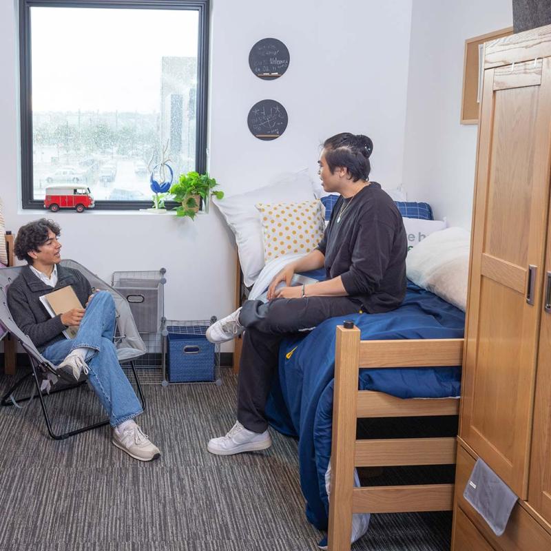 Two students sitting in dorm room talking