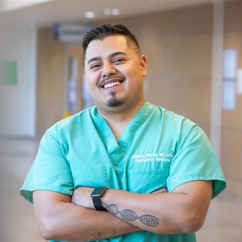 CU Denver alum, Will Mundo, posing in scrubs at work. 