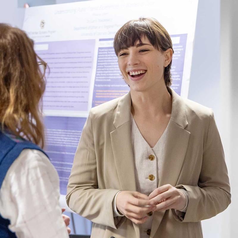 Woman in business casual attire speaking at conference