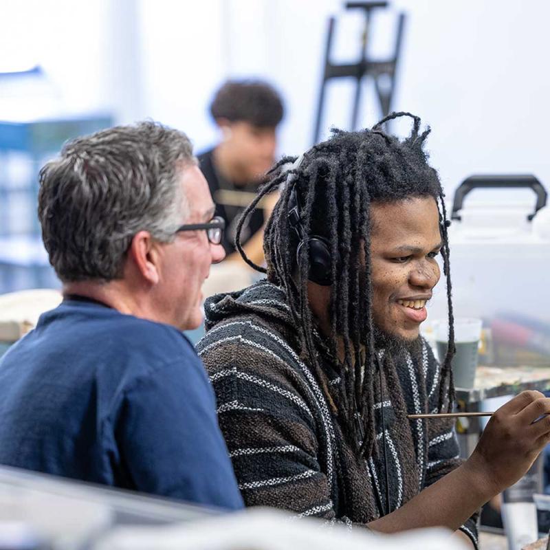 College of Arts and Media student painting picture with professor's help