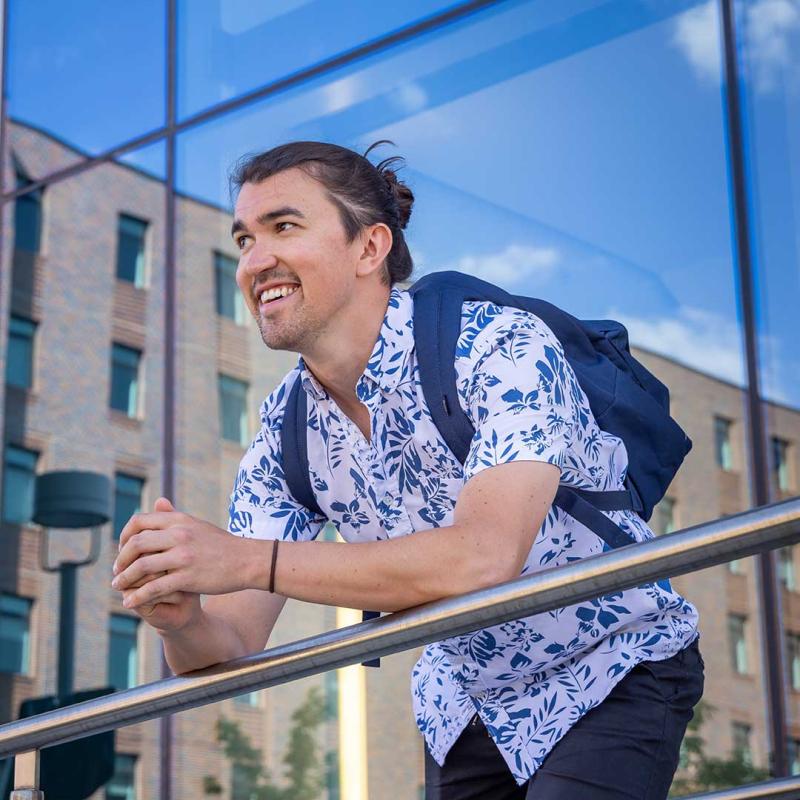 Student wearing backpack leaning over hand rail