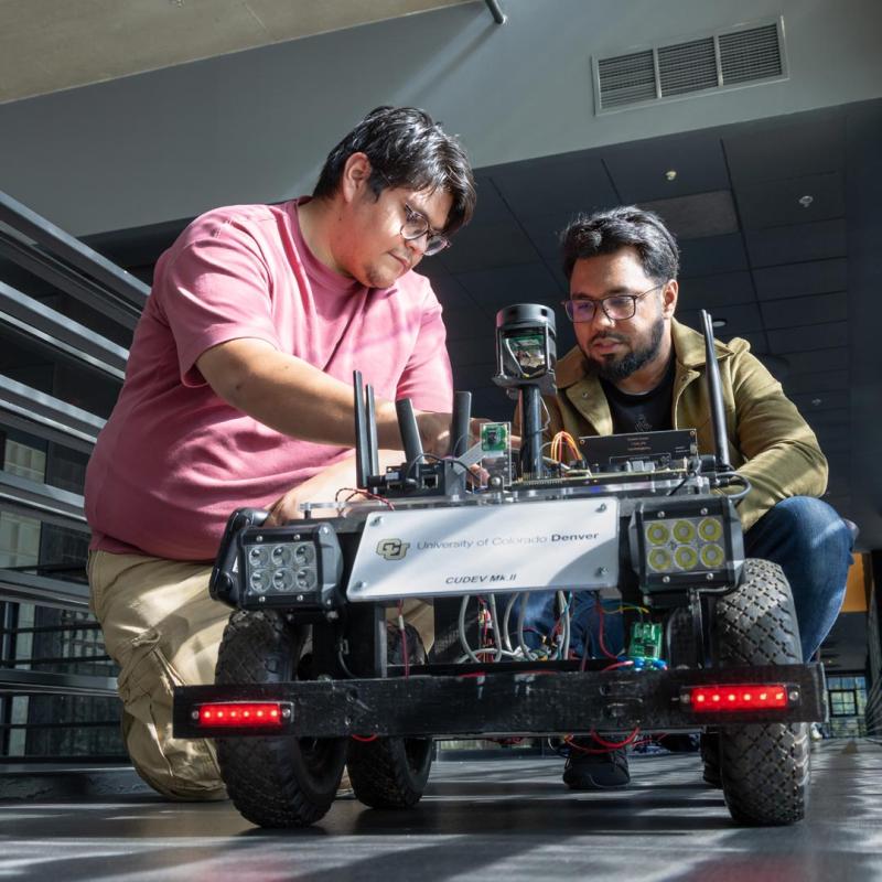 Two CU Denver students working on a robot
