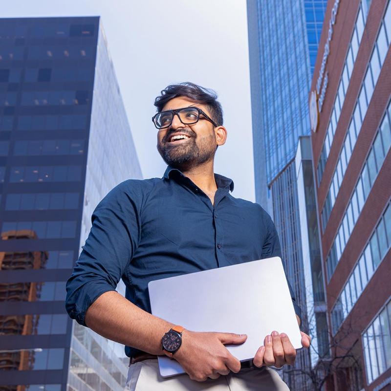 Student holding laptop on street in Denver, Colorado