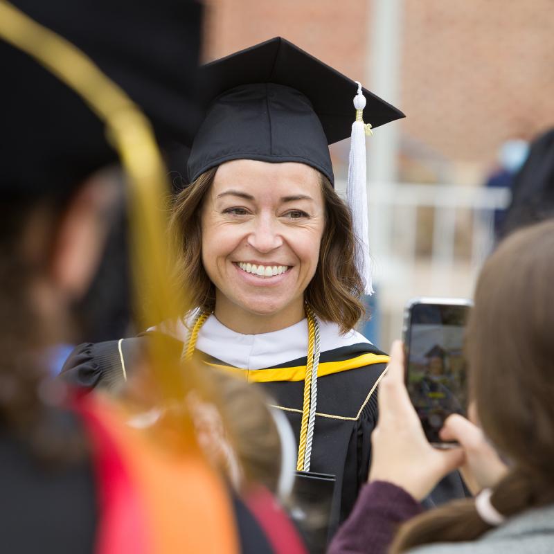 Graduate student smiling with cap and gown