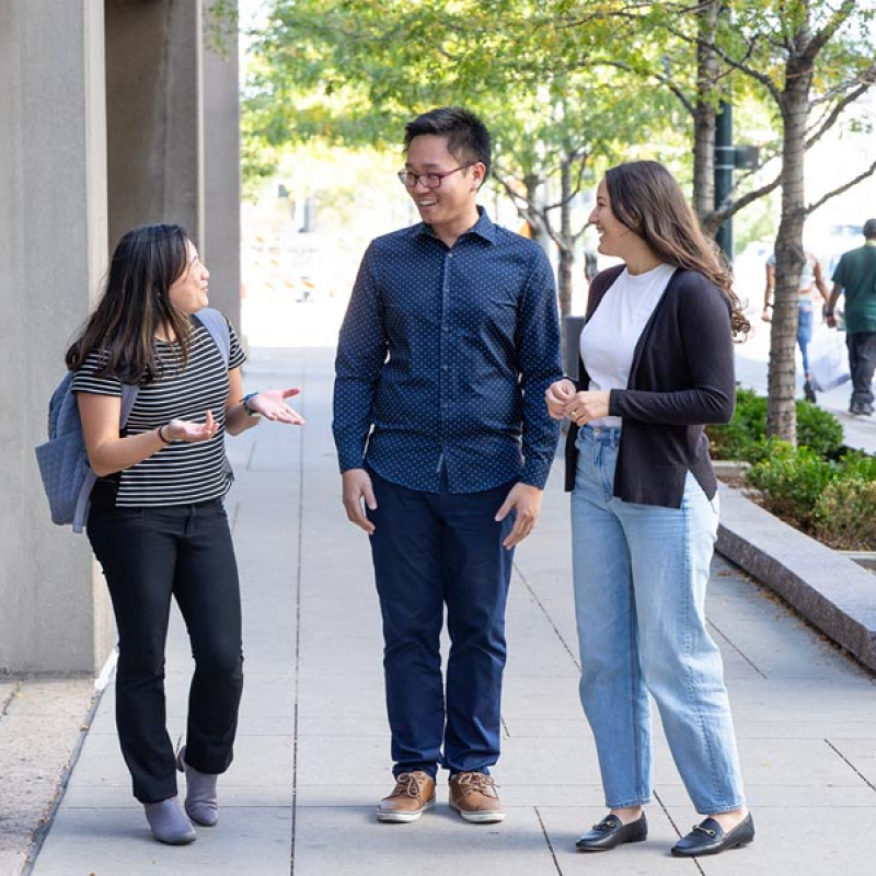 Three CU Denver students talking while standing outside of building on sidewalk
