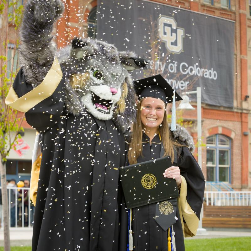 Milo the mascot with a graduate student and confetti