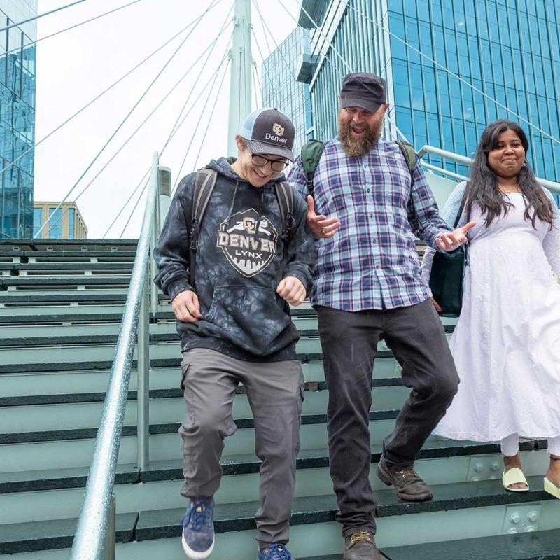Three students walking down steps outside