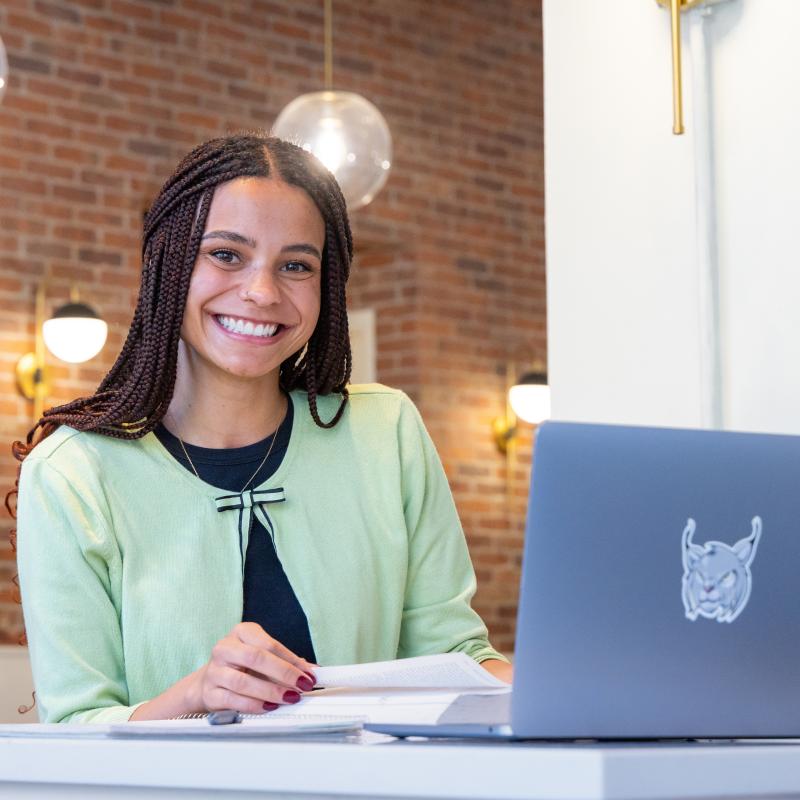 Student sitting in front of laptop smiling at camera